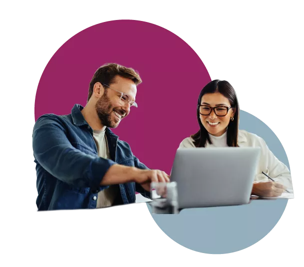  Man pointing at computer screen while colleague looks on smiling